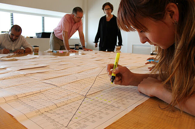 Workshop participants work on surveys on a table. 