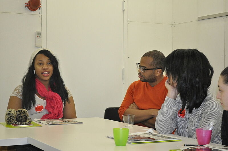 The artist listens to a student speak around a table.