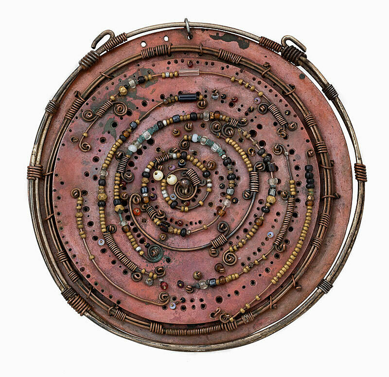 A round sculpture with beads and wire creating a spiral.