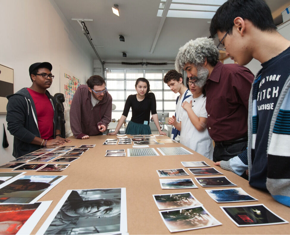 Fred Wilson talking to students over a table of artwork.