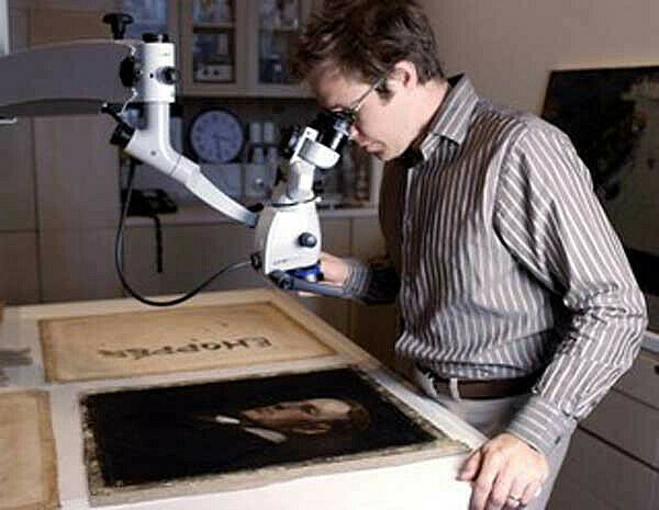 man looking at portrait through microscope