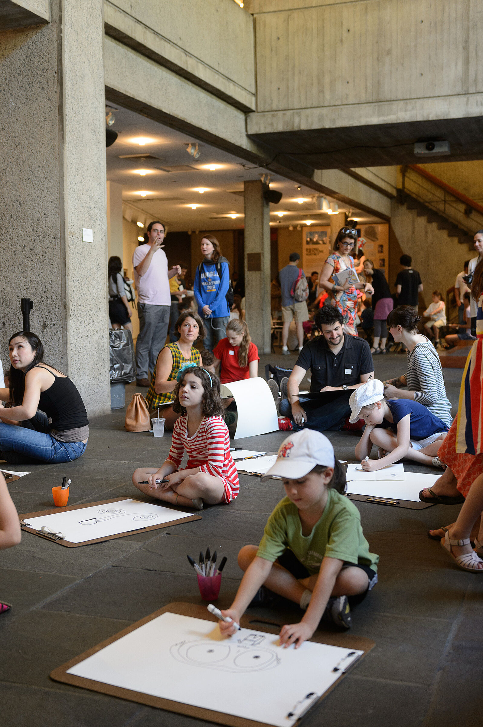 Kids sit on the ground in the museum and draw