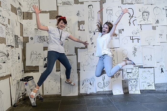 Two staff members jump in the gallery