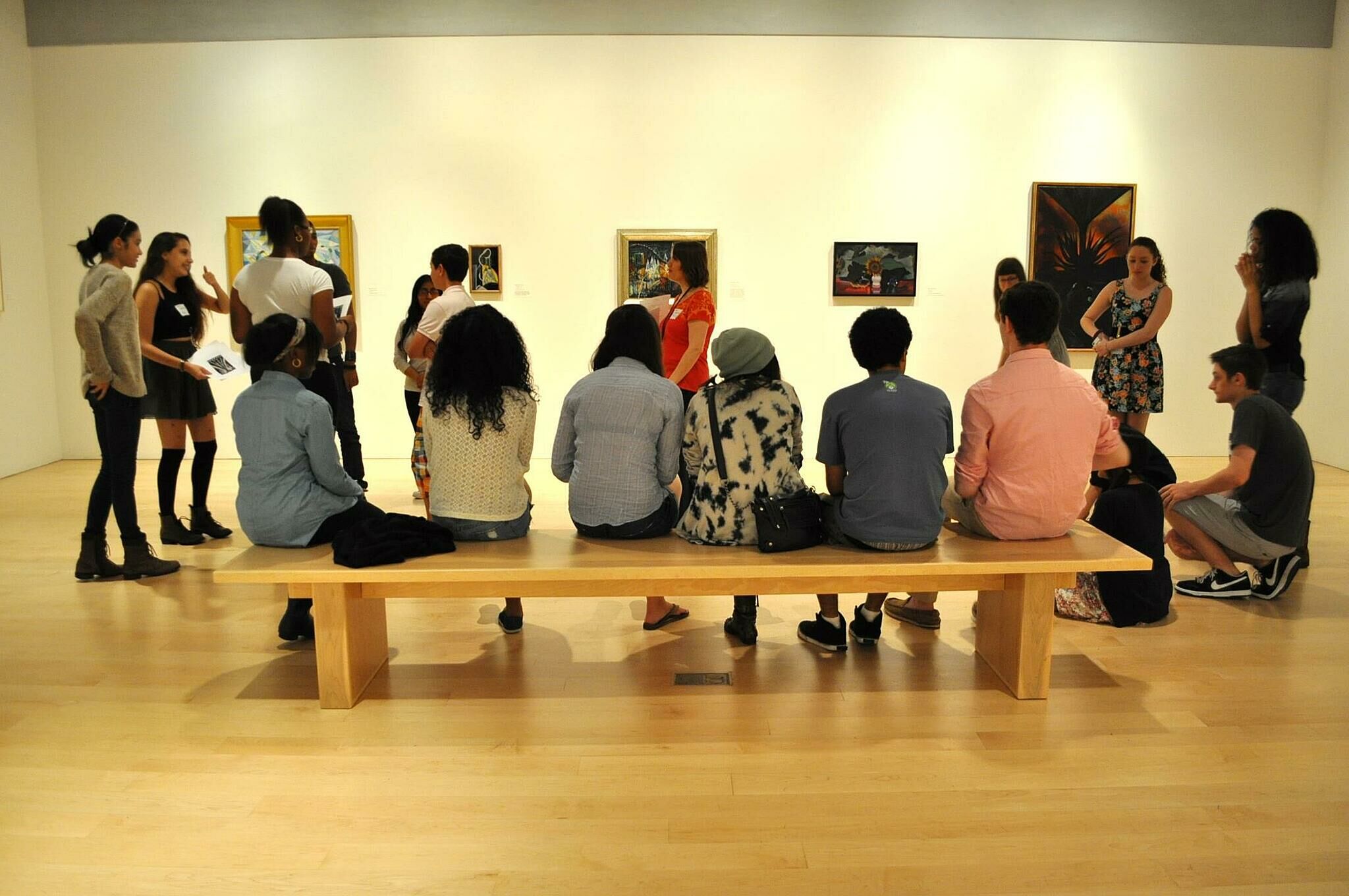 kids sit on bench in gallery room