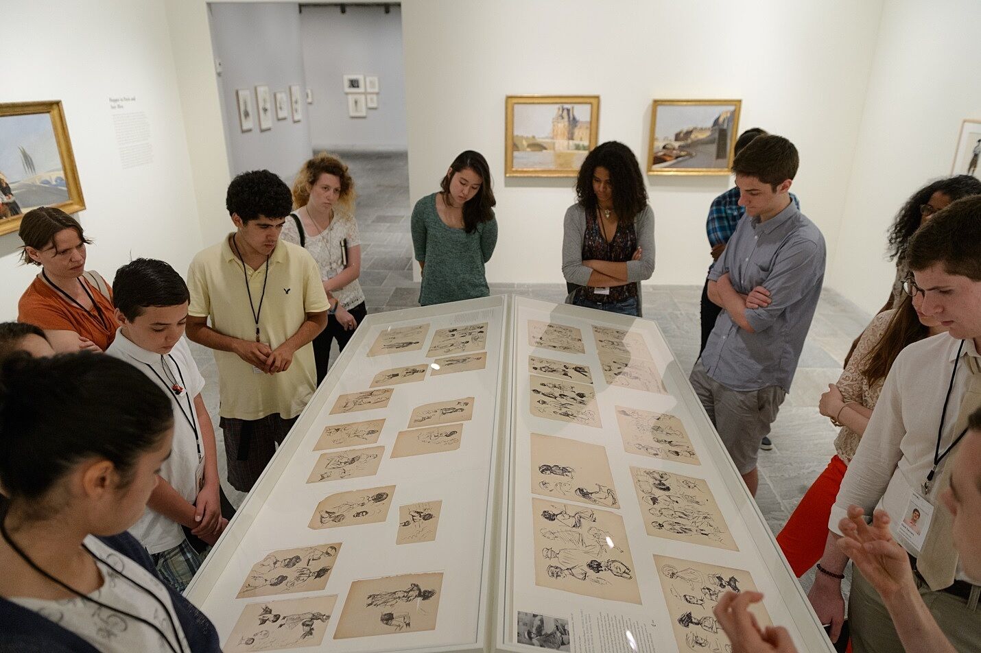 A student tour group gathers around drawings by Edward Hopper.
