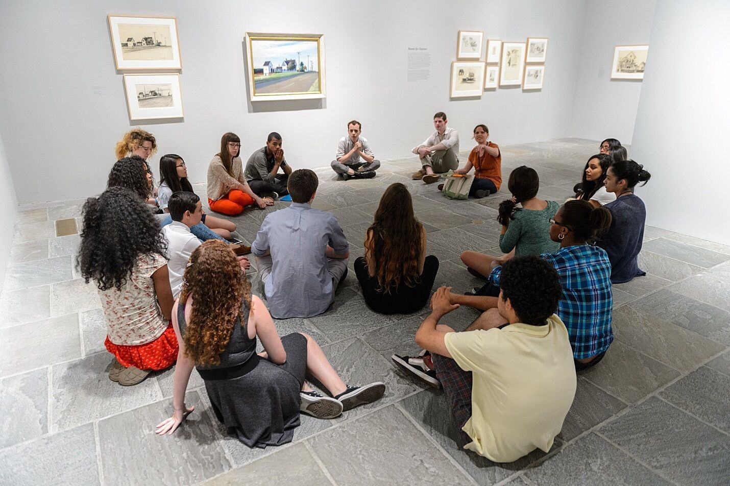 A group of students sits on the gallery floor in the Edward Hopper exhibit.