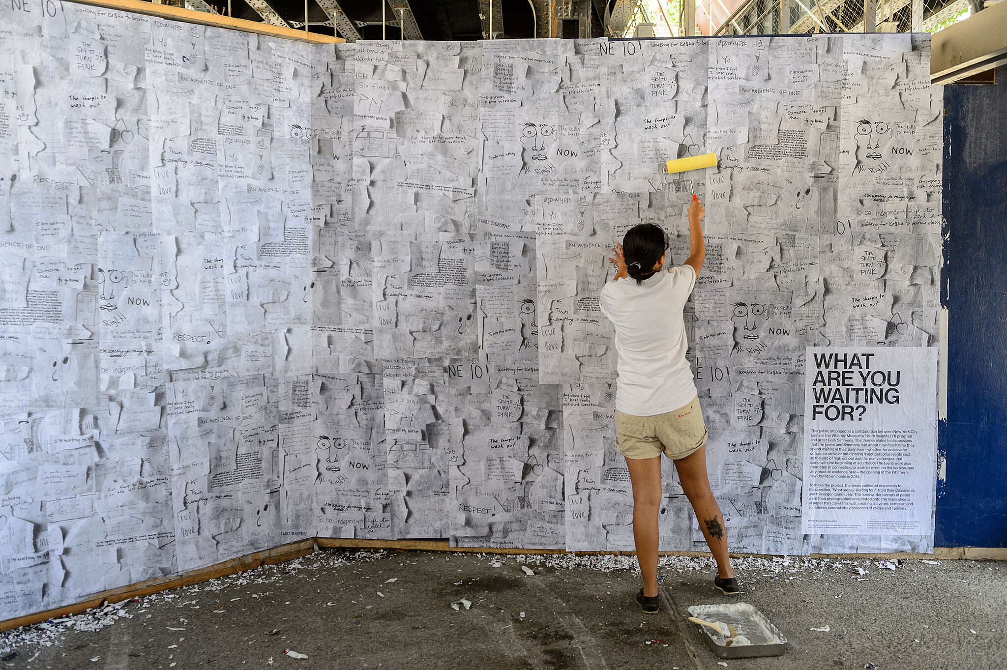 teen pasting paper to a wall