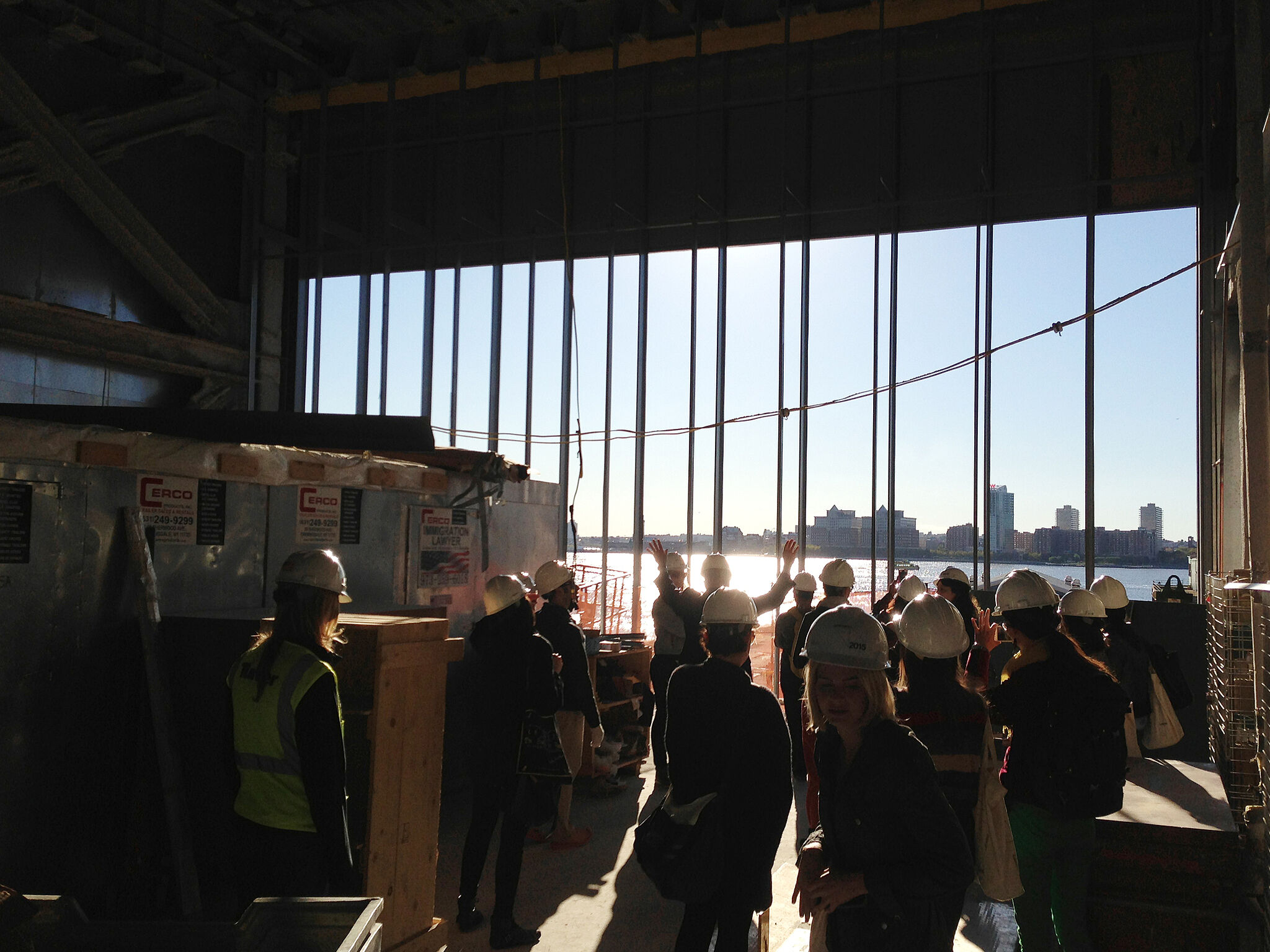 A tour group watches the sunset from inside the Whitney under construction