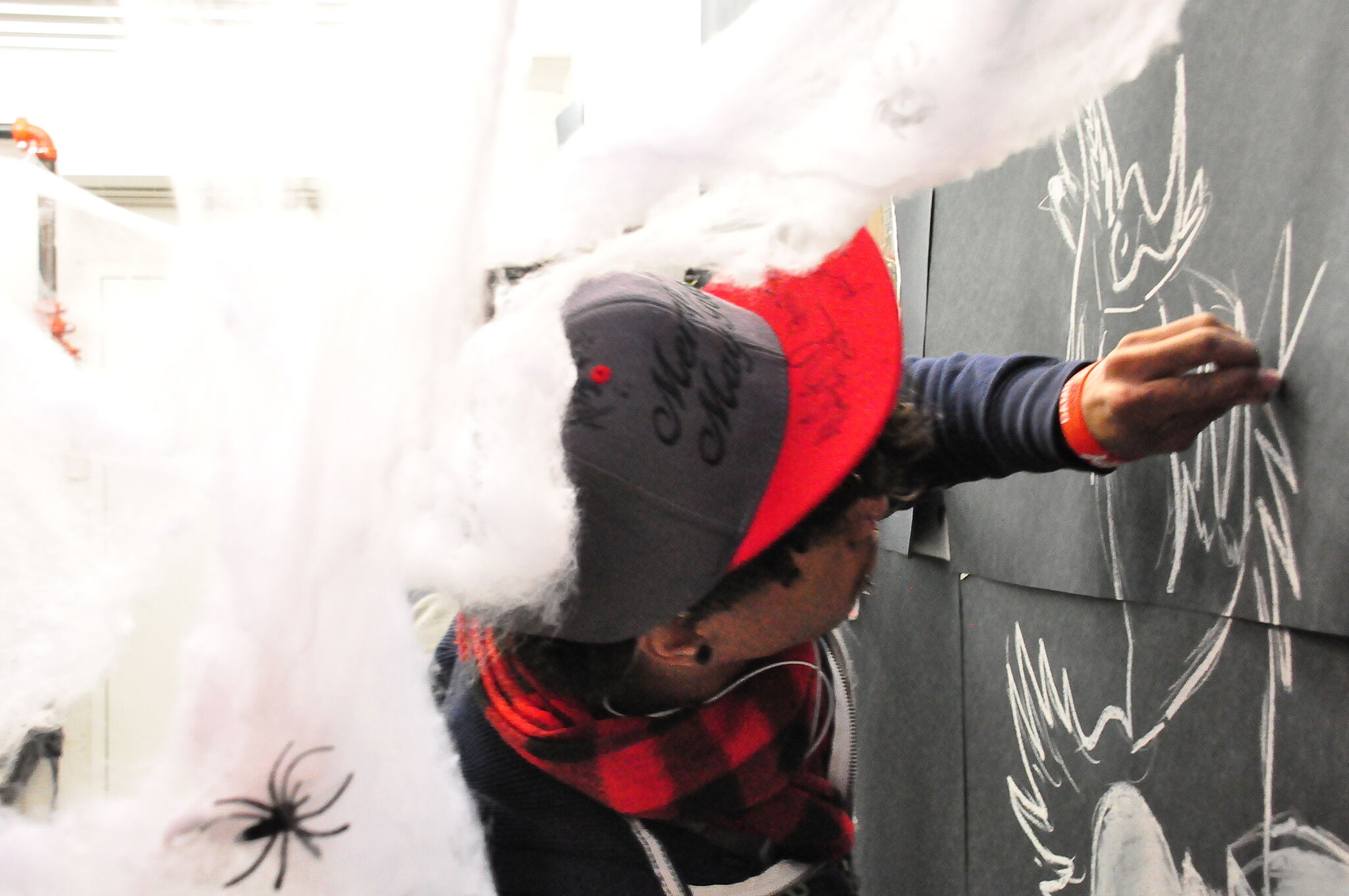 teen writing on wall with cobwebs behind