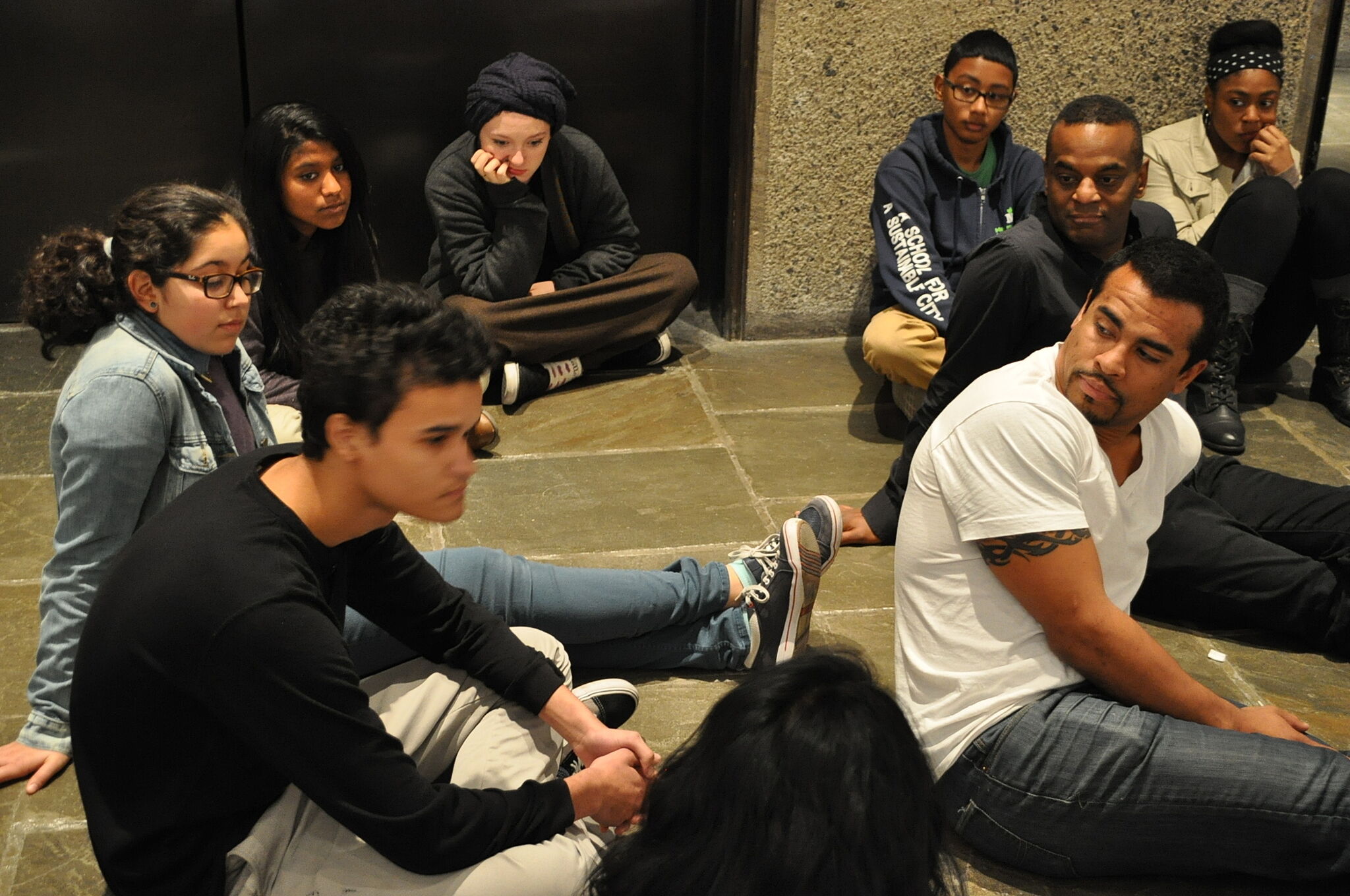 students and artist sit on floor 