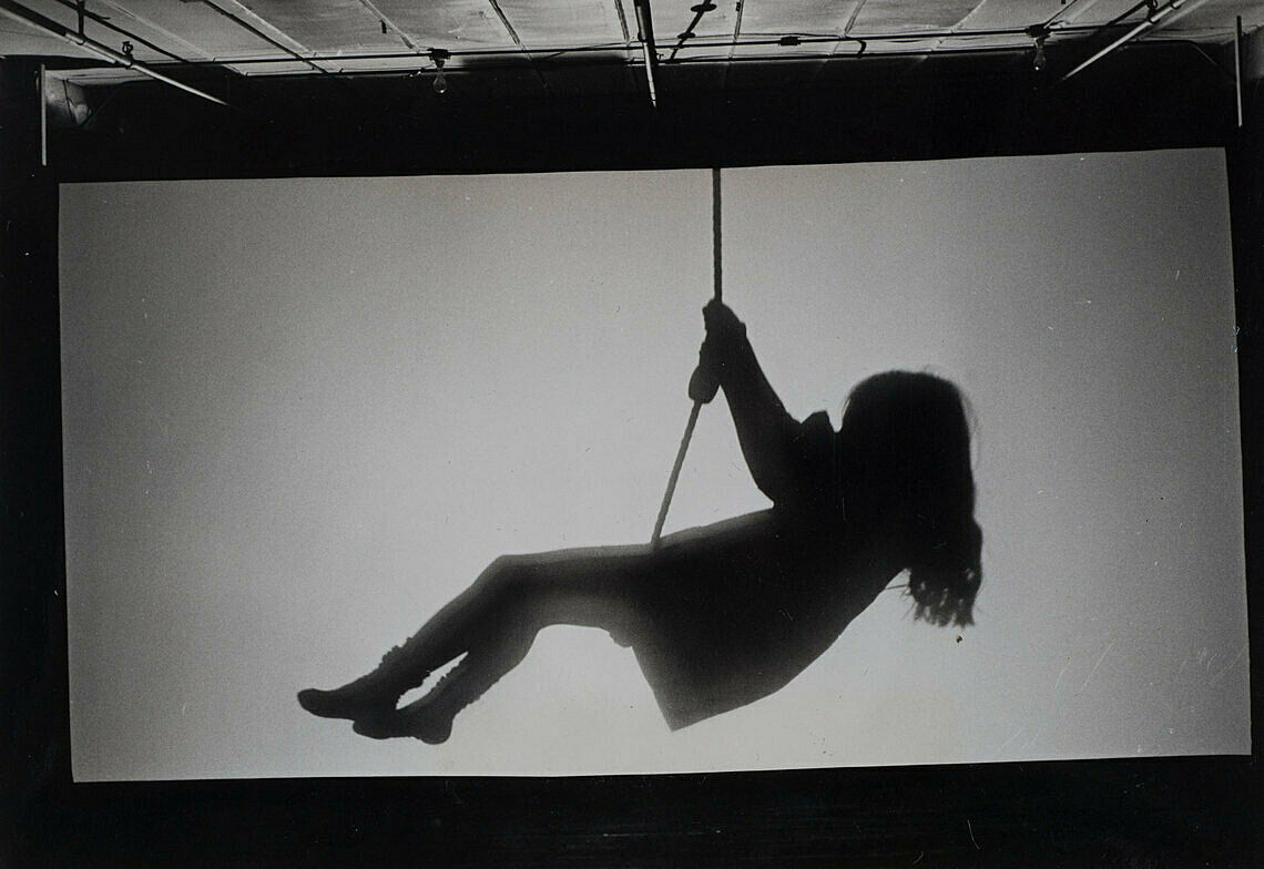 A projection of a little girl on a swing in silhouette.