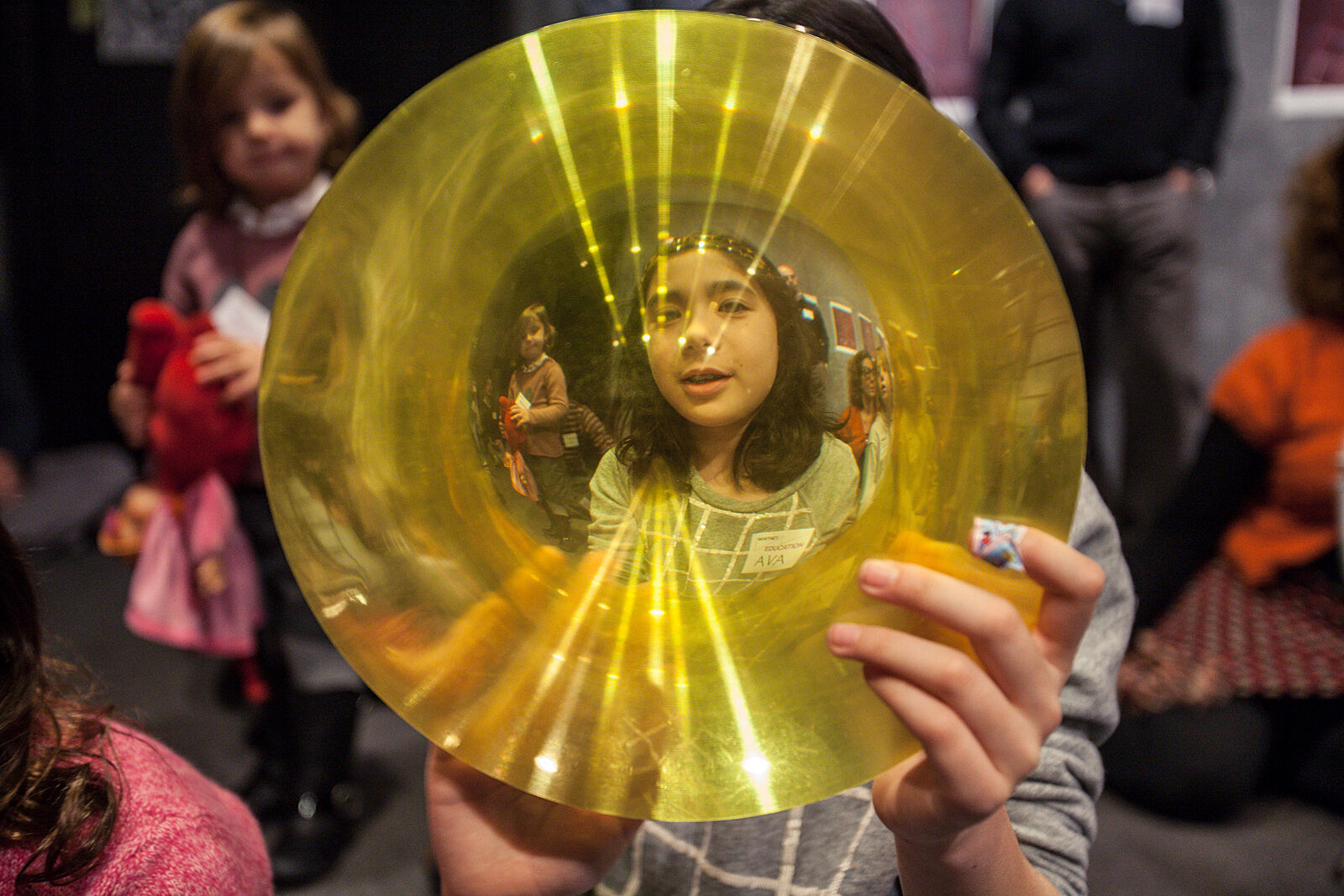 A child holds up a piece of yellow glass