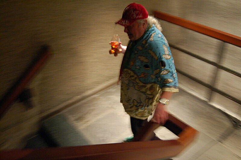 A man walking downstairs holding a glass of drink. 
