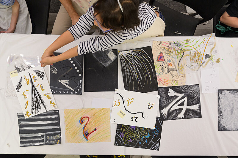 Pages of children's art are laid out on a table