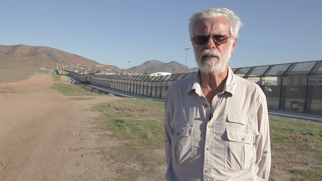 The artist Fred Lonidier standing at the border between the US and Mexico