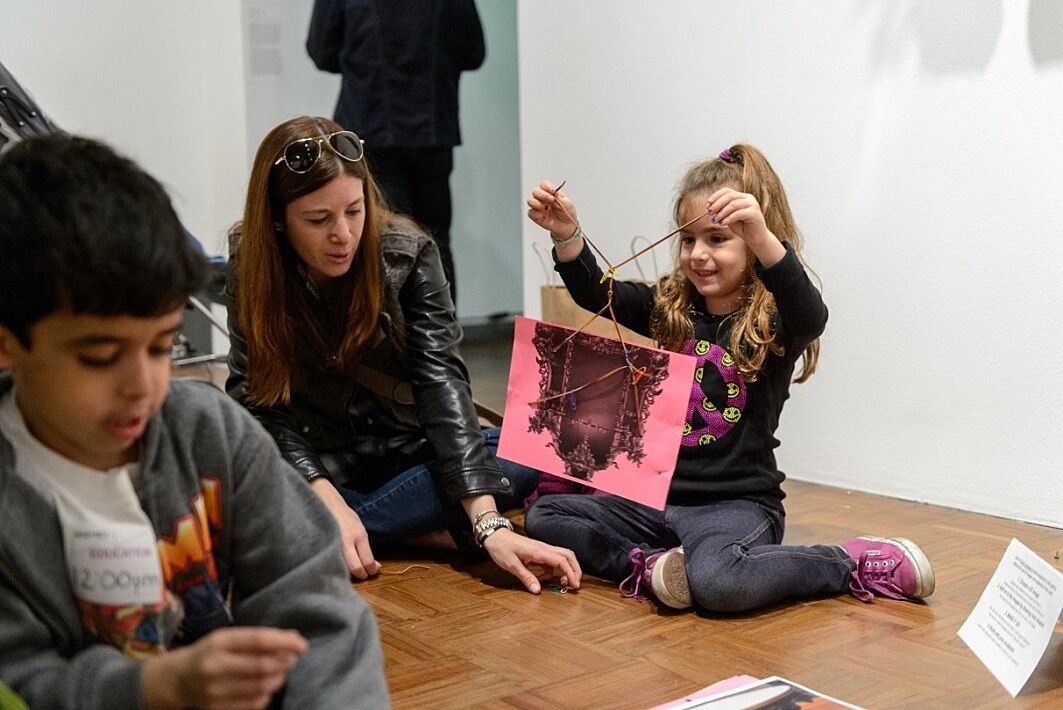 A girl hold up her art project in a gallery.