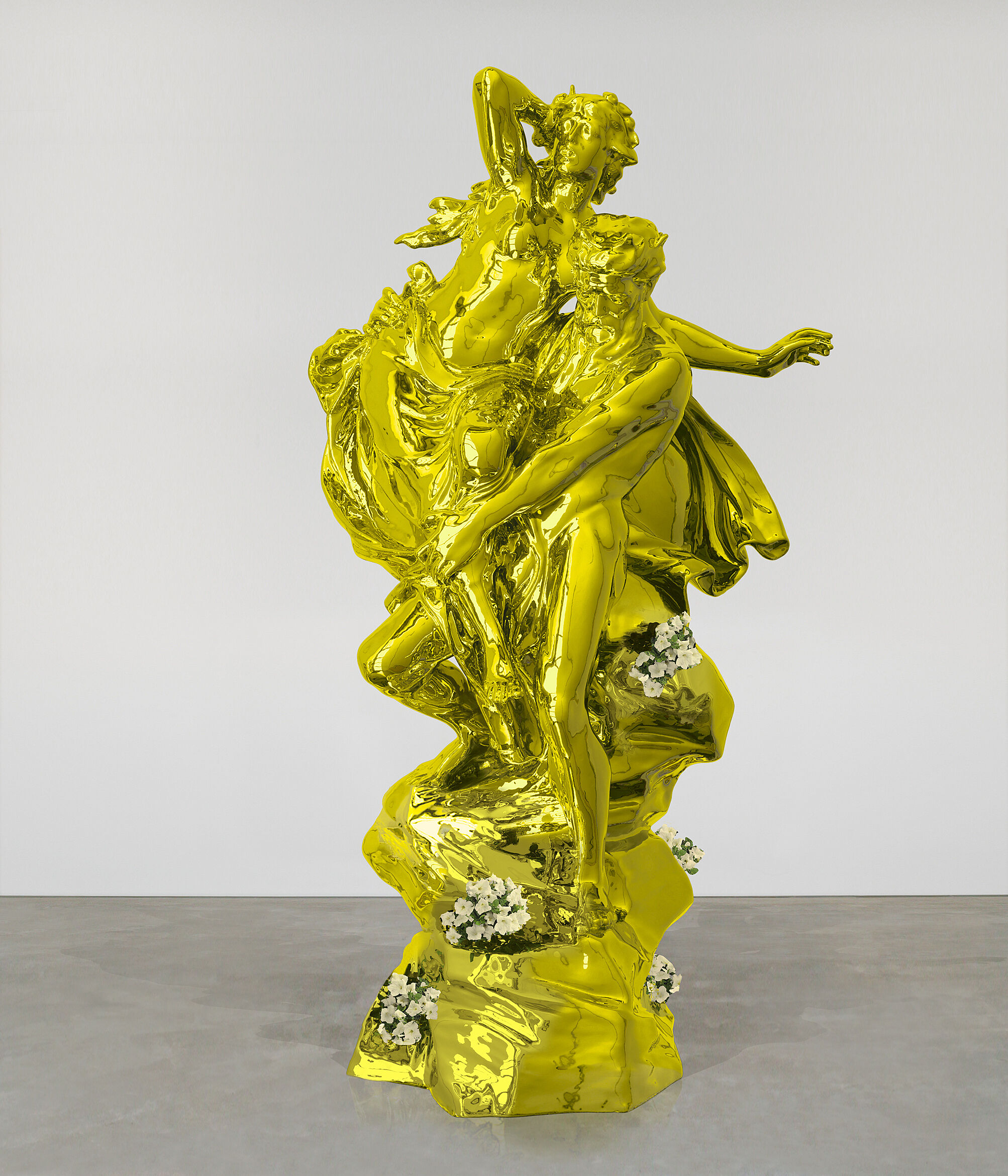 A yellow-golden statue of two figures, one holding the other, with live plants scattered around the base.