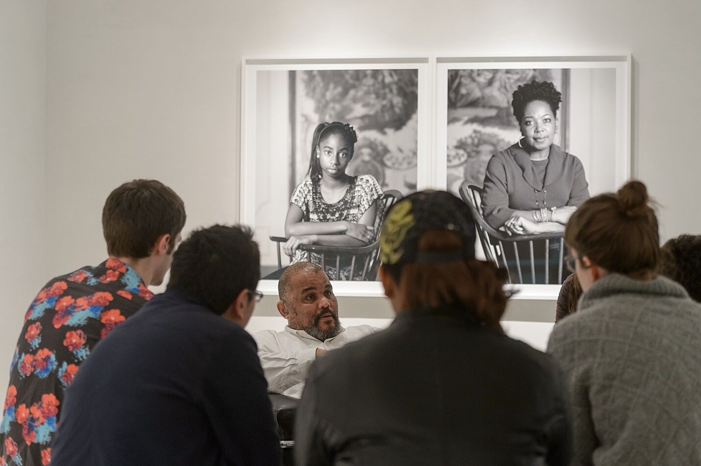 Dawoud Bey talks to teen leaders in a gallery with a photo behind him.