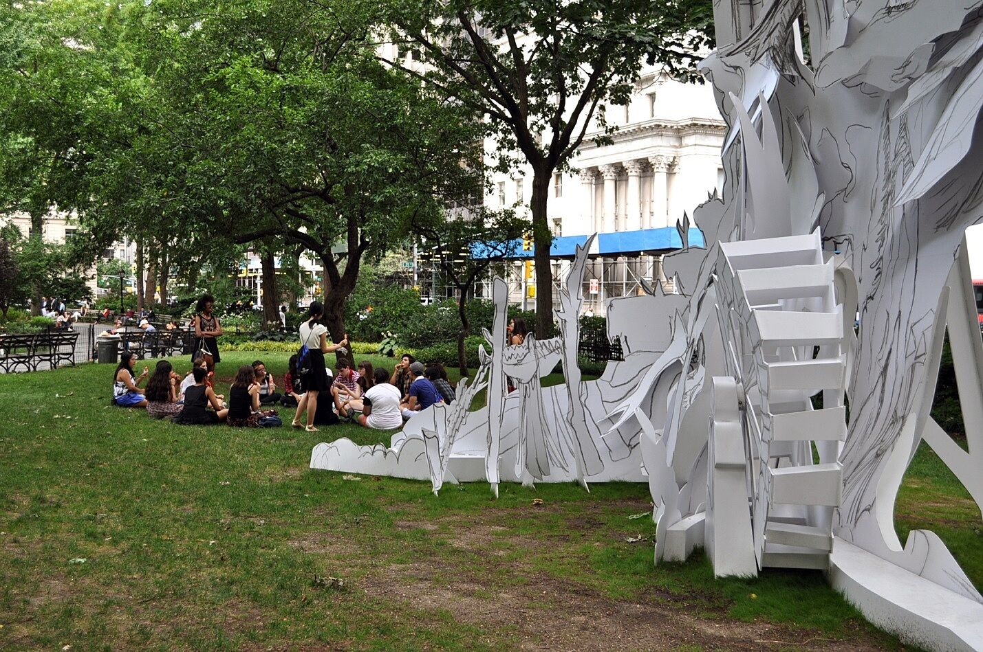 teens sitting in park next to installation