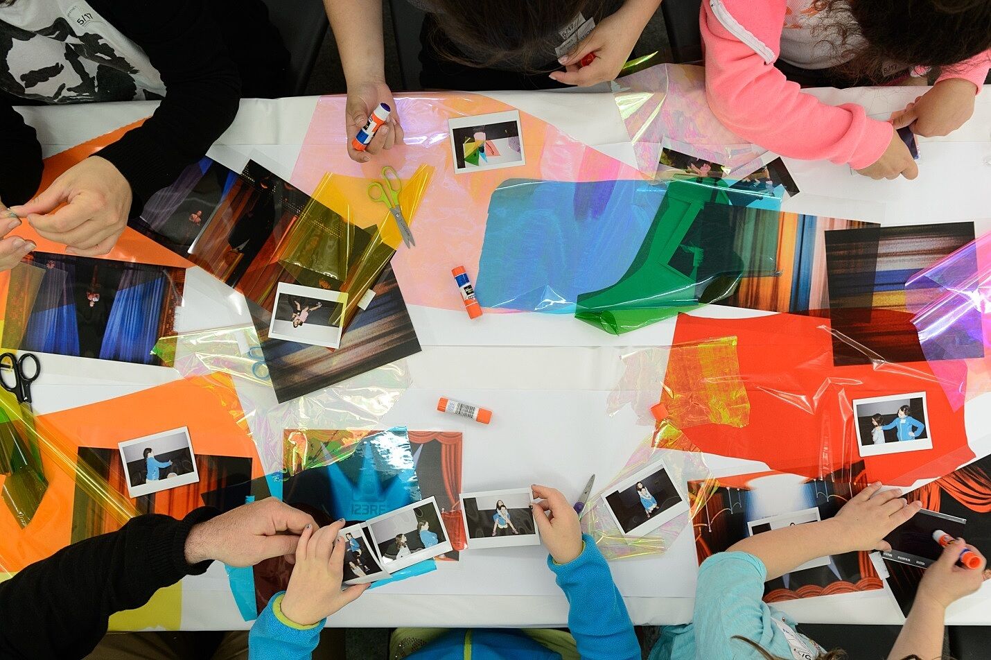 Children experiment with photographs, glue, and colored translucent paper.