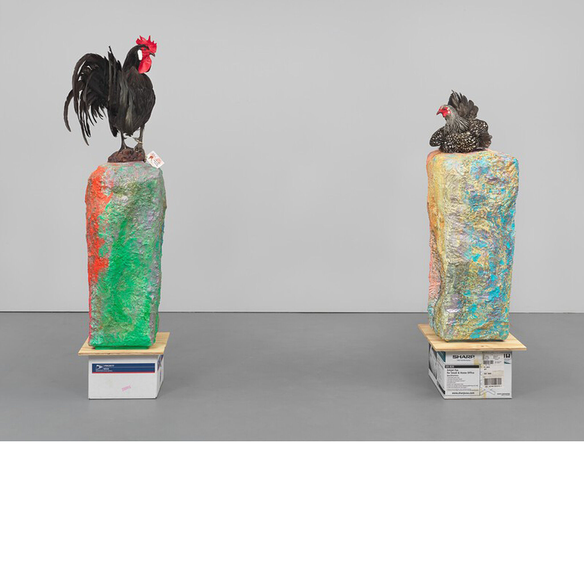 Rooster and chicken statues on top of colorful tablets.