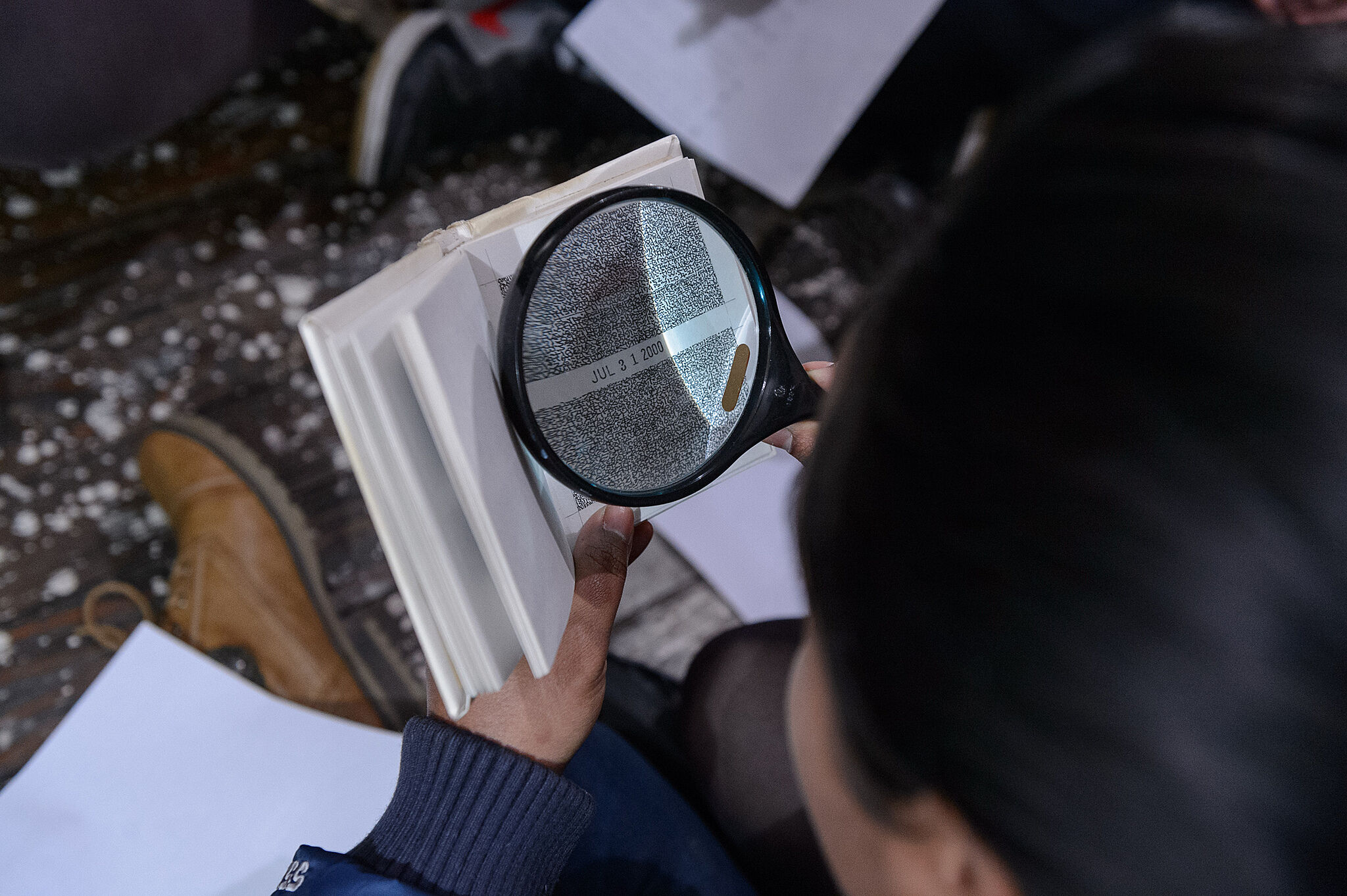student with magnifying glass looking at a book