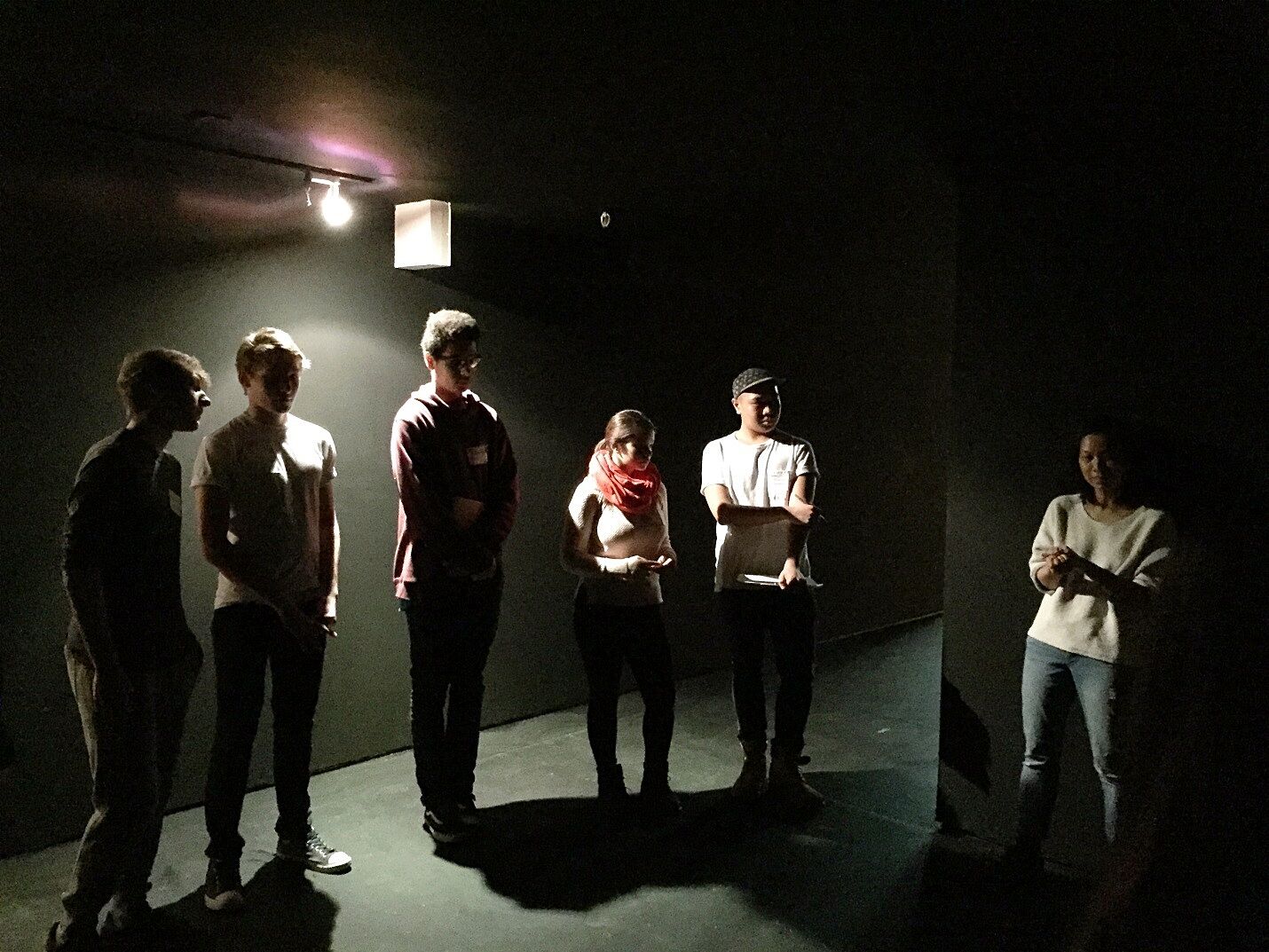 teens standing in darkly lit room