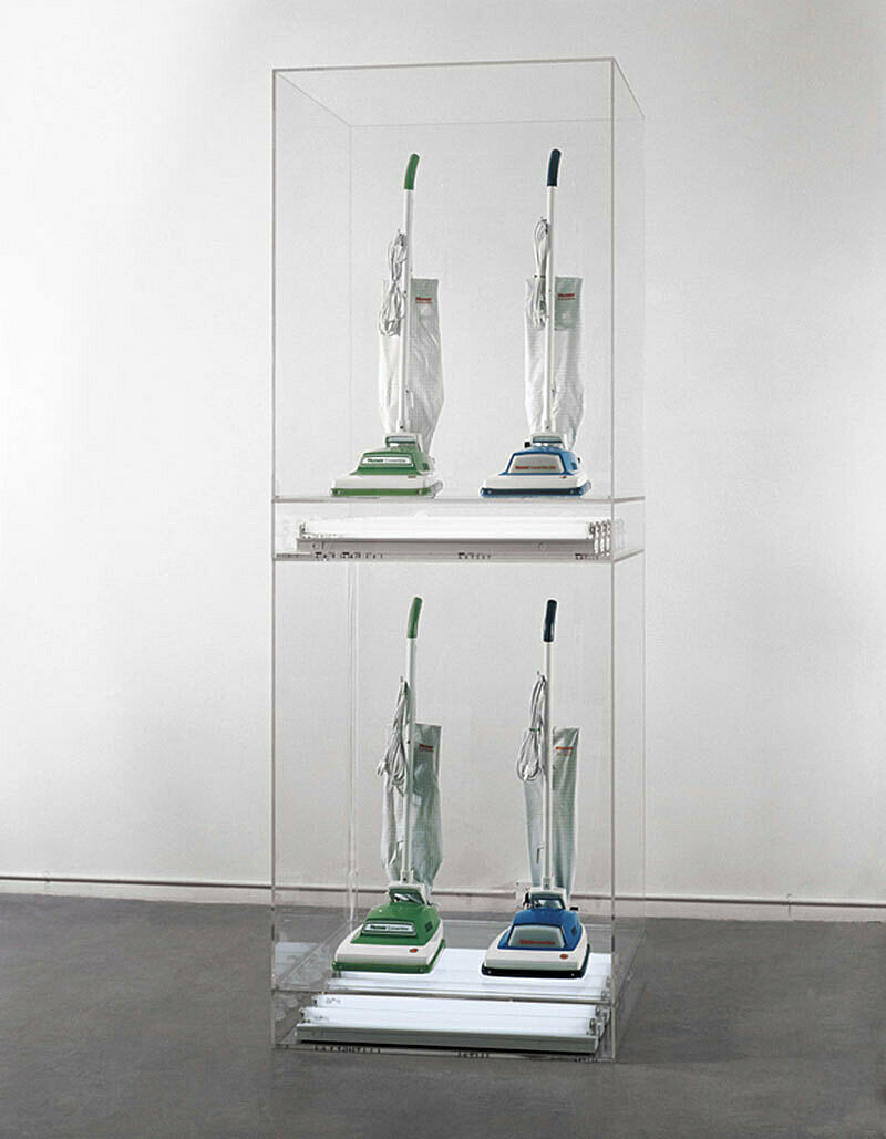 An installation of 4 vacuum cleaners in a glass case.