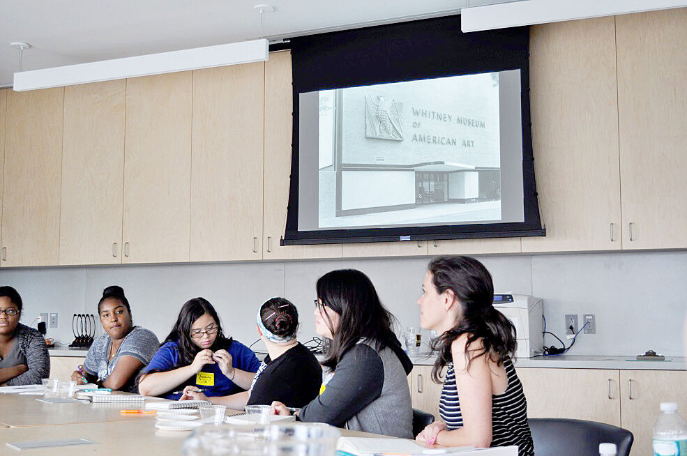 Teens look at a slide show about the history of the Whitney Museum.