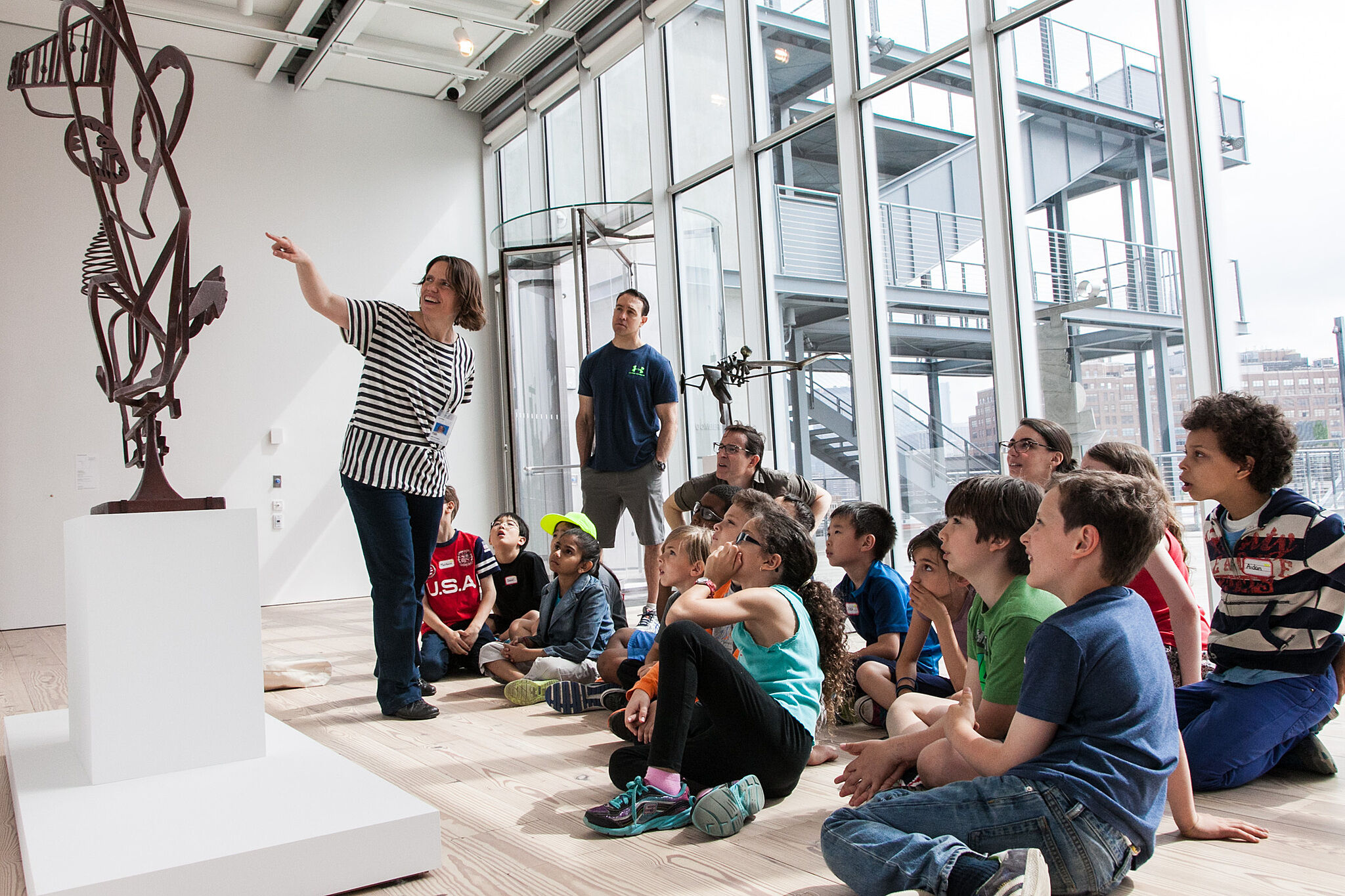 children sit in front of a abstract sculpture