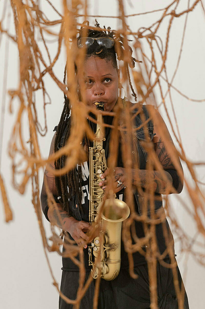 A person playing a saxophone amongst artwork in a gallery.