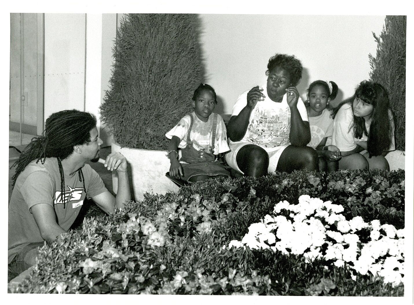 An artist talks to a family in a garden art installation.
