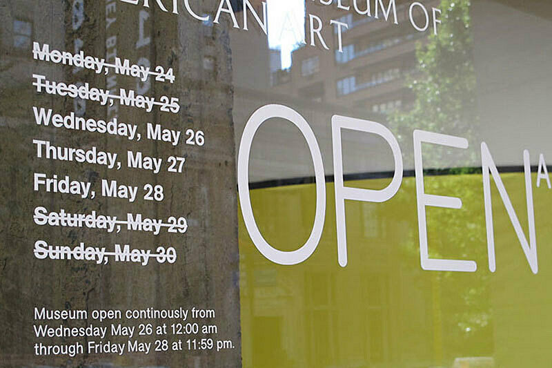 Words printed on the museum glass advertising that the museum is open continuously for three days