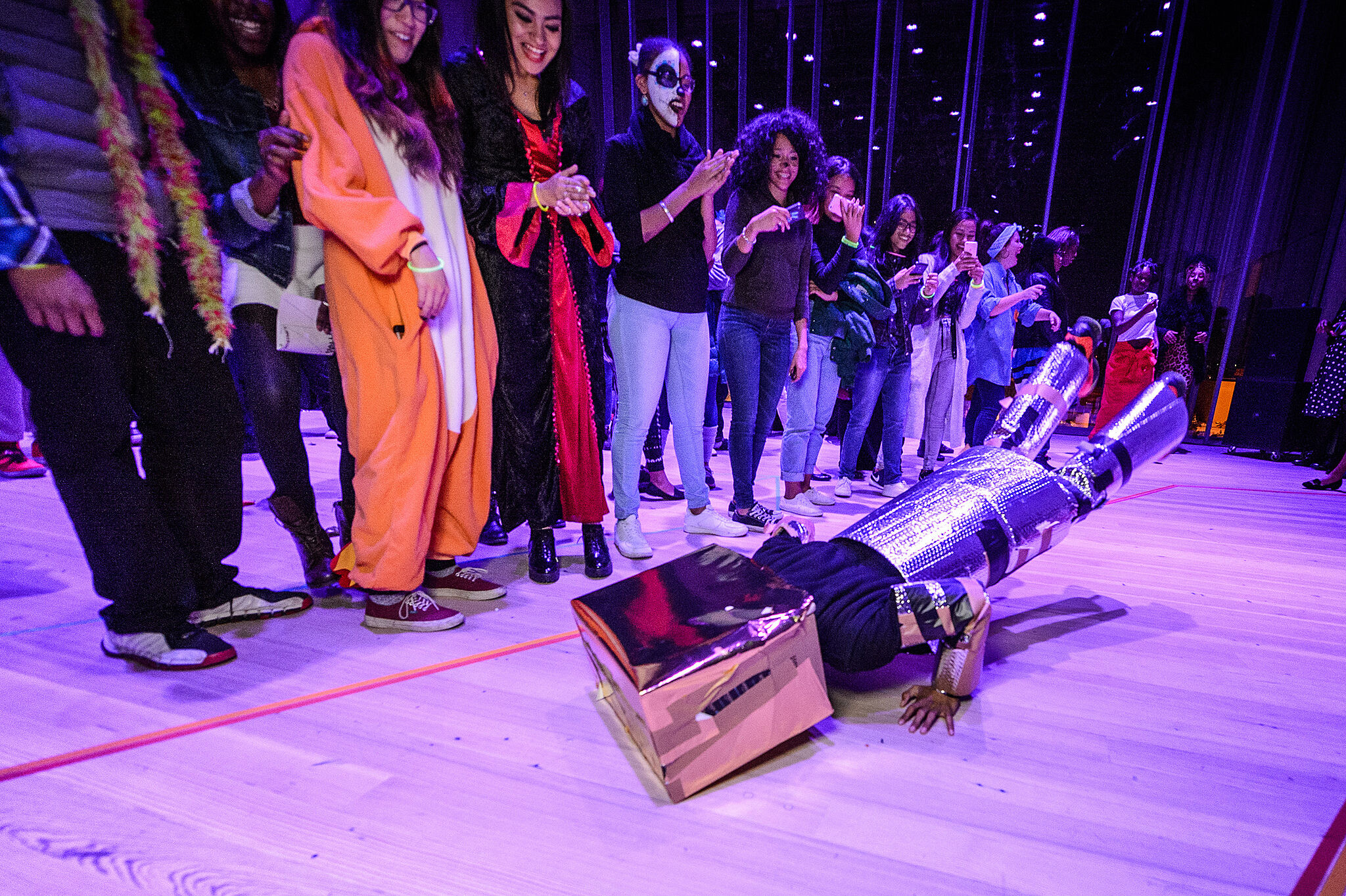 A dancer does the robot while teens in costume watch.