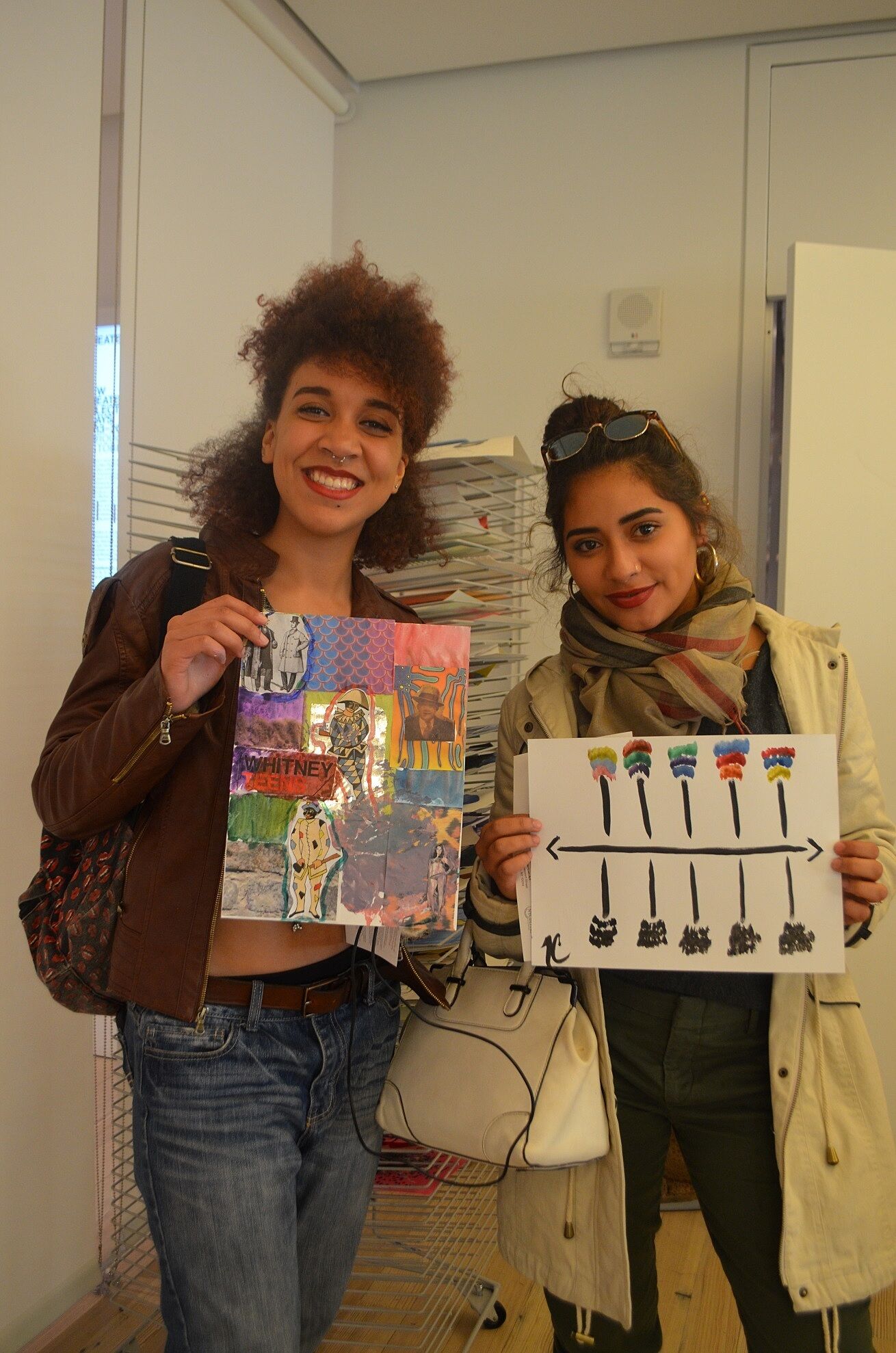 two teens holding up their artwork