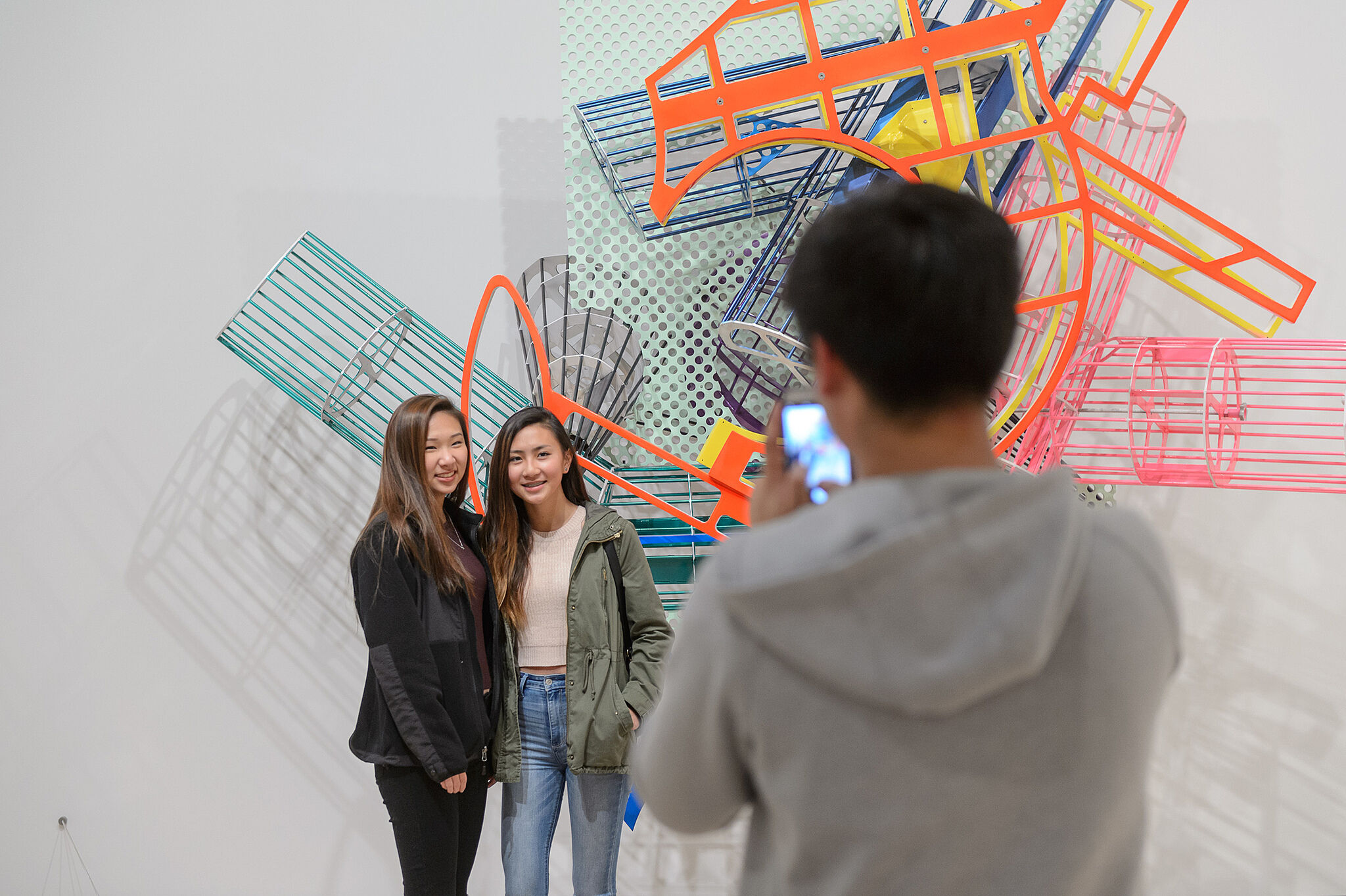 Two girls pose in front of a Frank Stella artwork. 