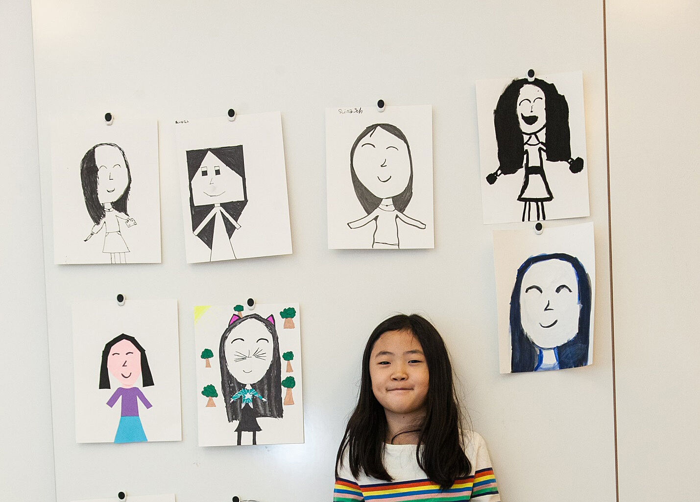A student posting with self-portraits at art camp