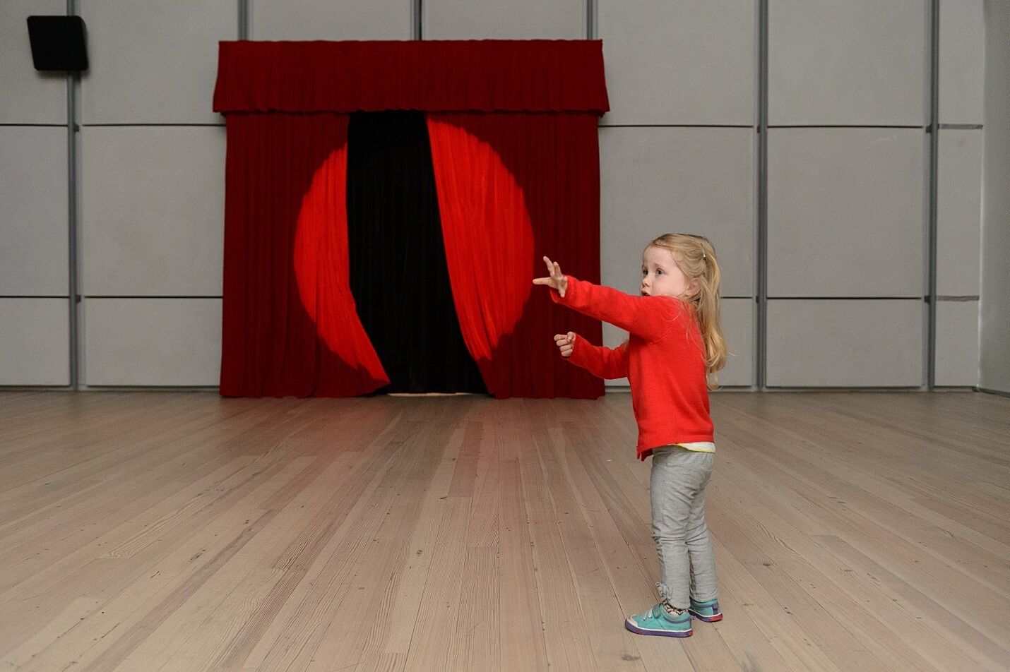 A child interacting with the curtains of the puppet theater