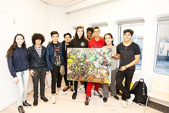 A teen group holds up their painting that they created together.