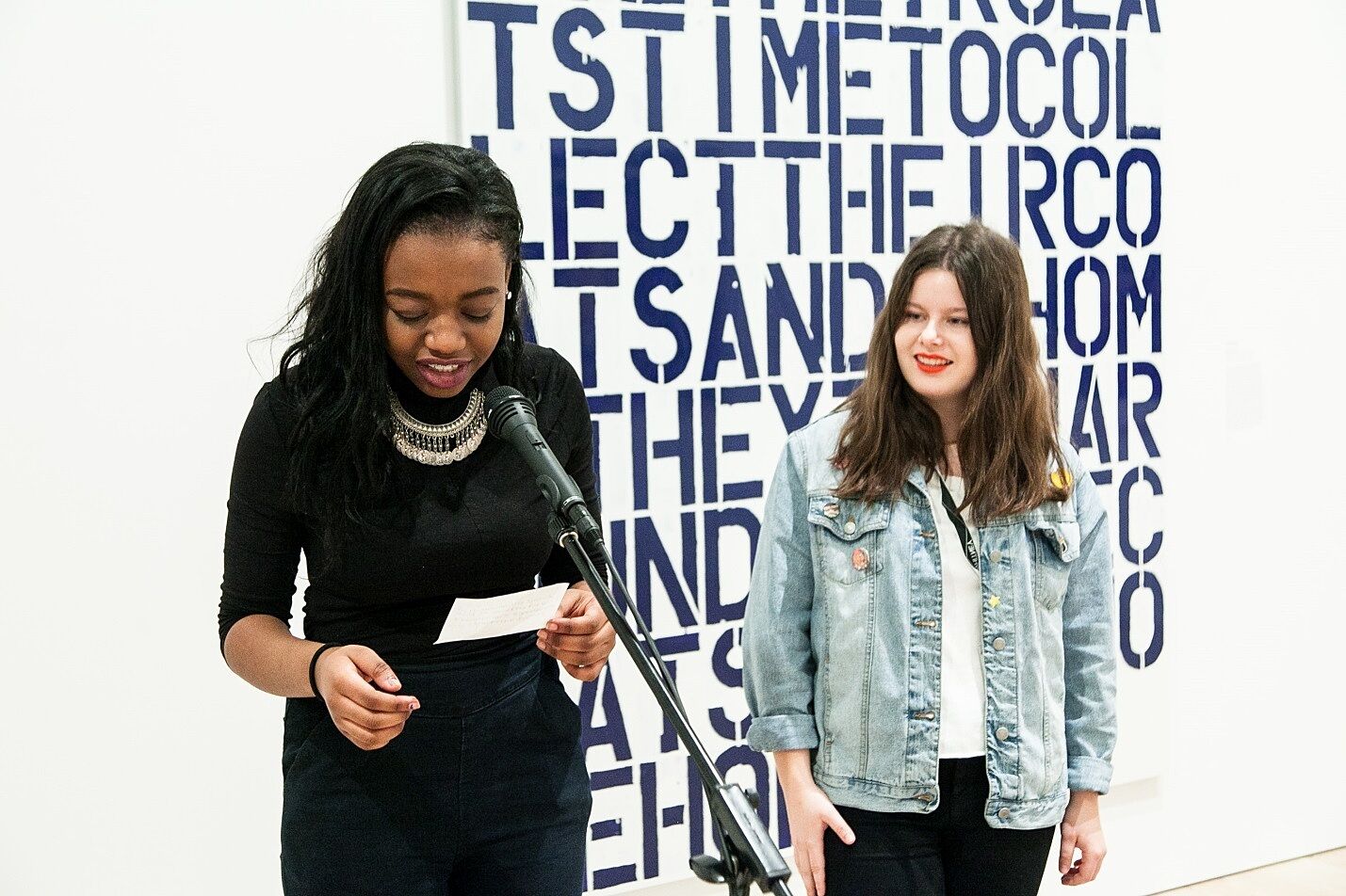 two teen presenting in front of a painting