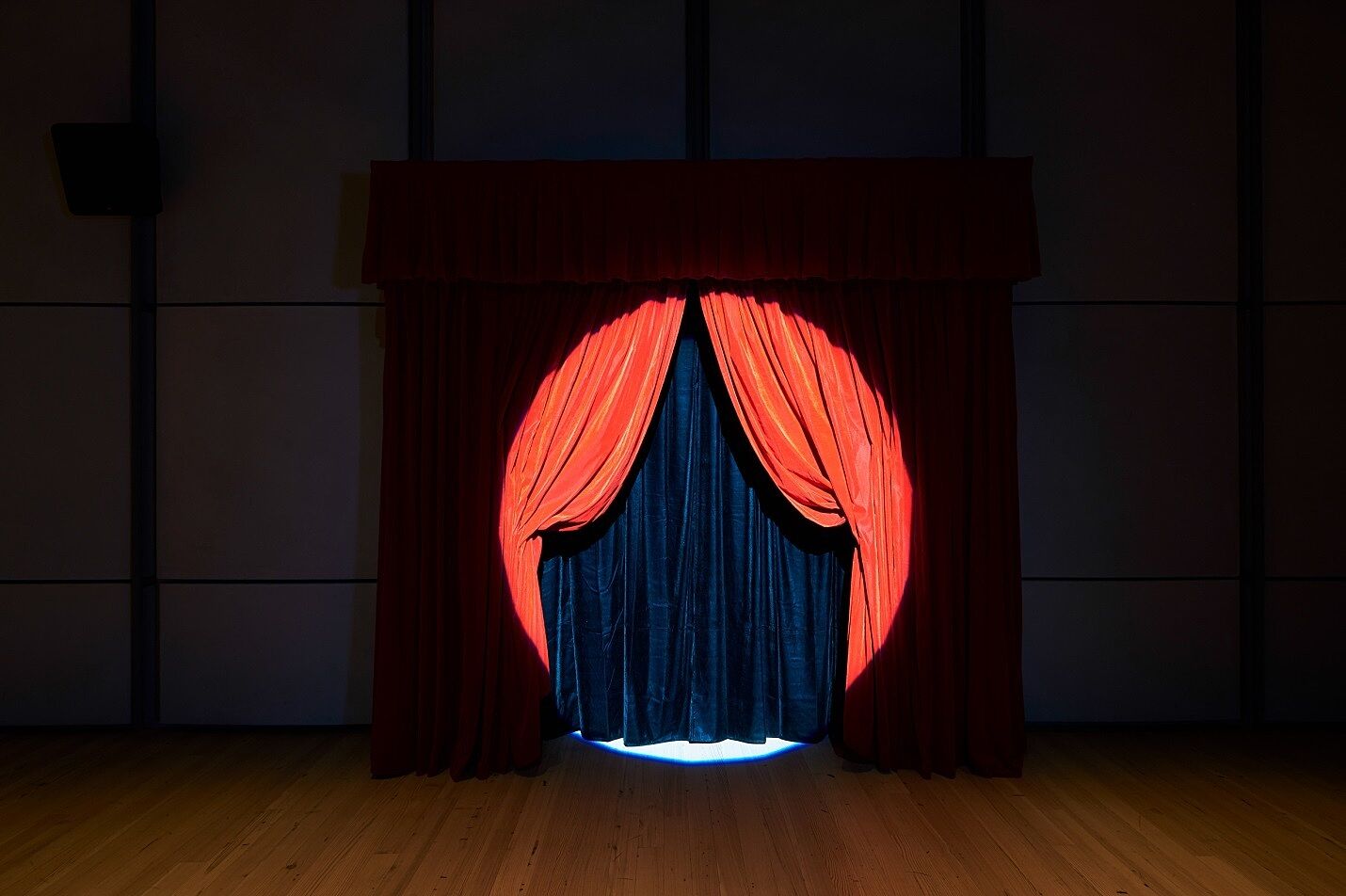 A spotlight shines on a stage curtain.