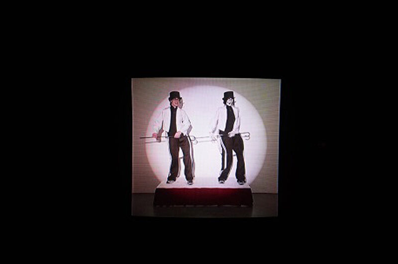 Video still of two dancers in a spotlight.