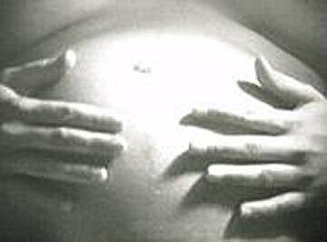 A film still of a pregnant person holding with their hands on their stomach.
