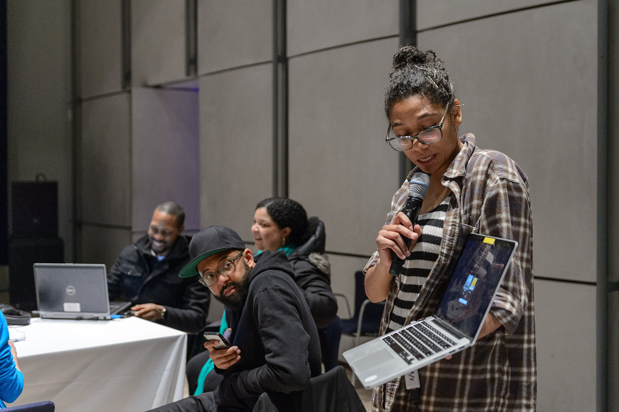 Harlo Holmes speaks into a mic while holding a laptop at a CryptoParty session