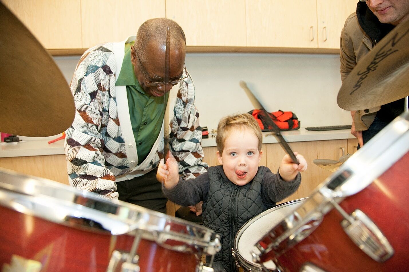 A child plays the drums with the help of drummer Andrew Cyrille