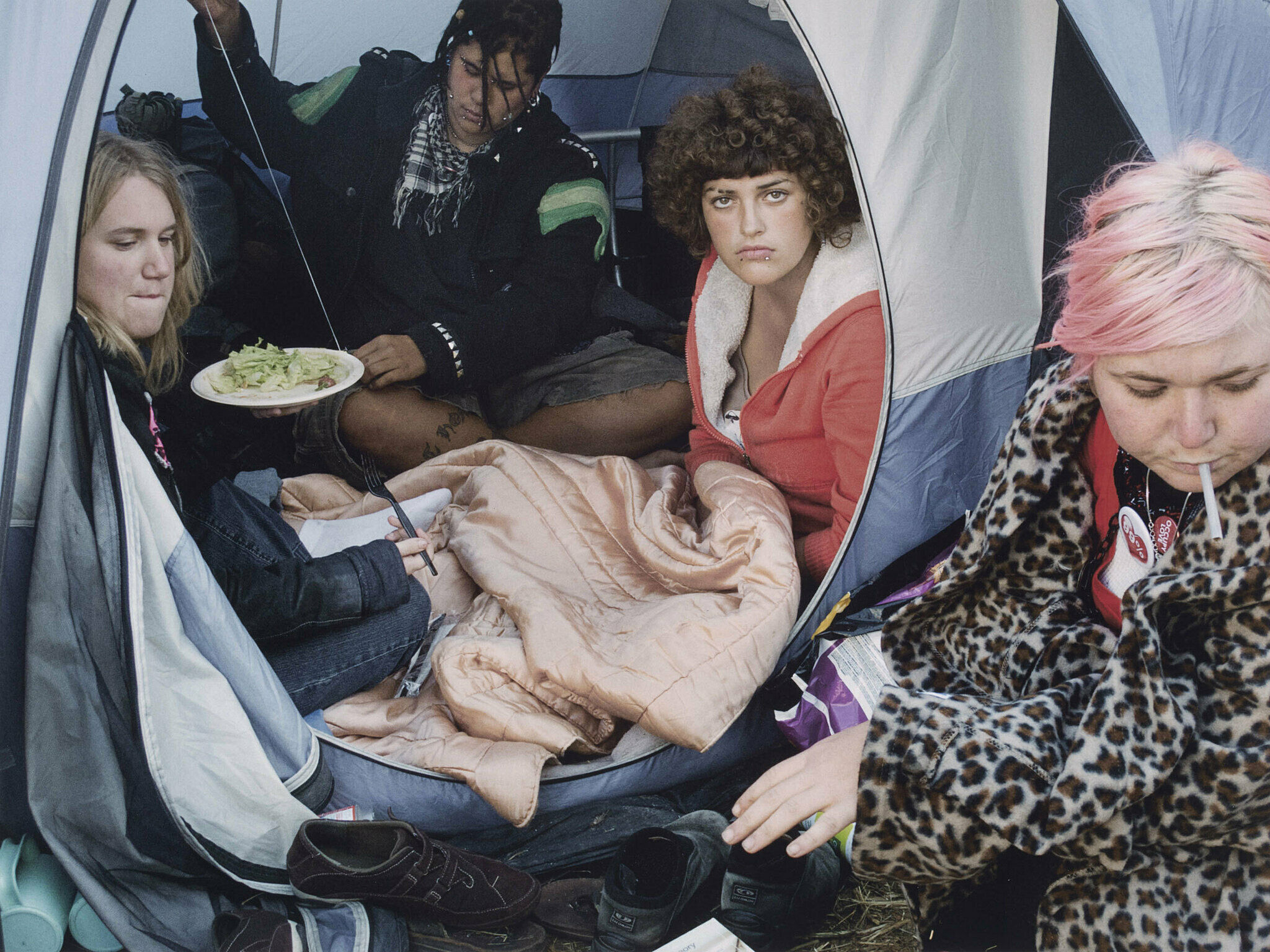 A photograph by Danny Lyon. Teenagers sit in a tent.