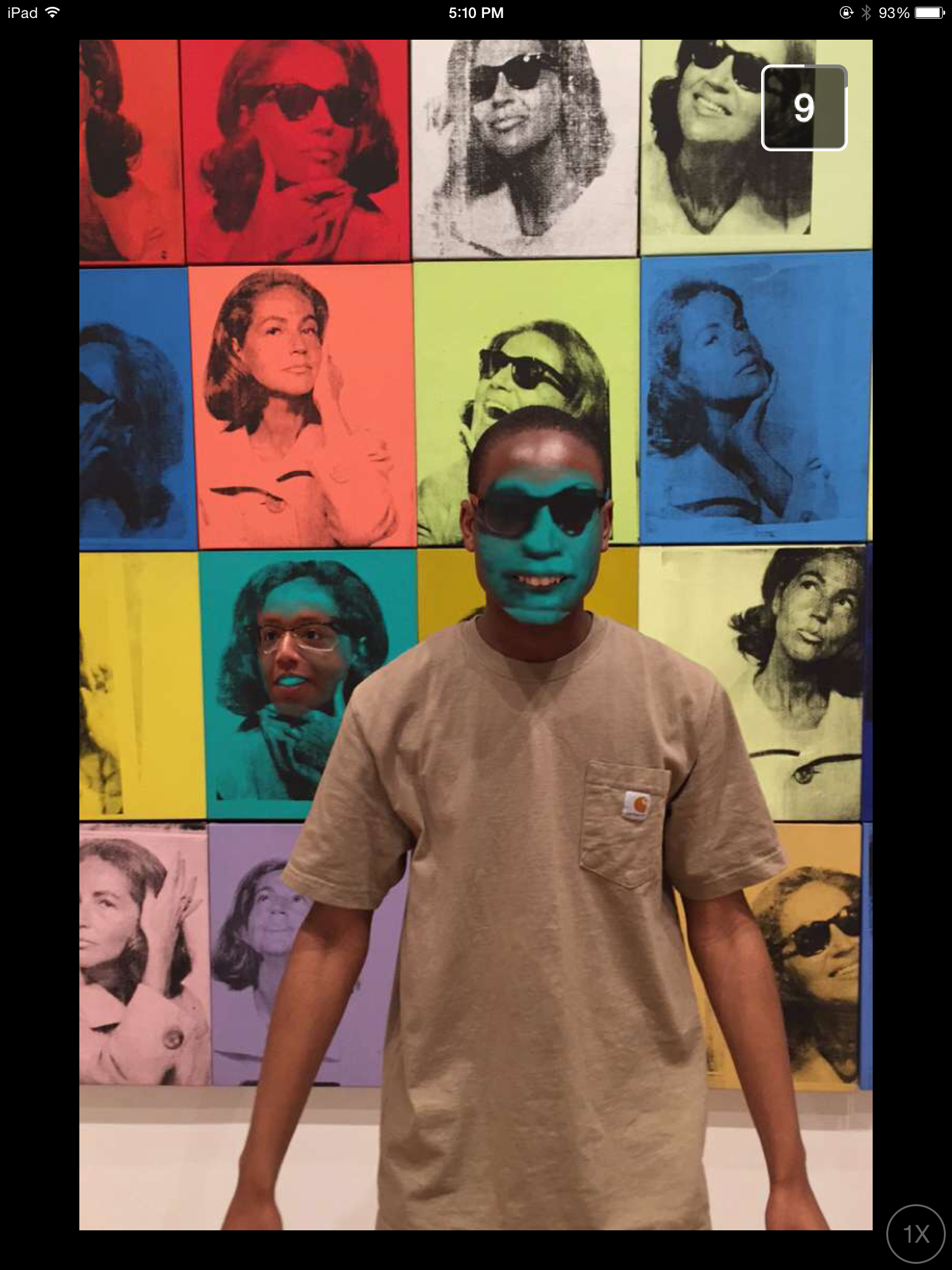 A teen with a blue mask in front of artwork