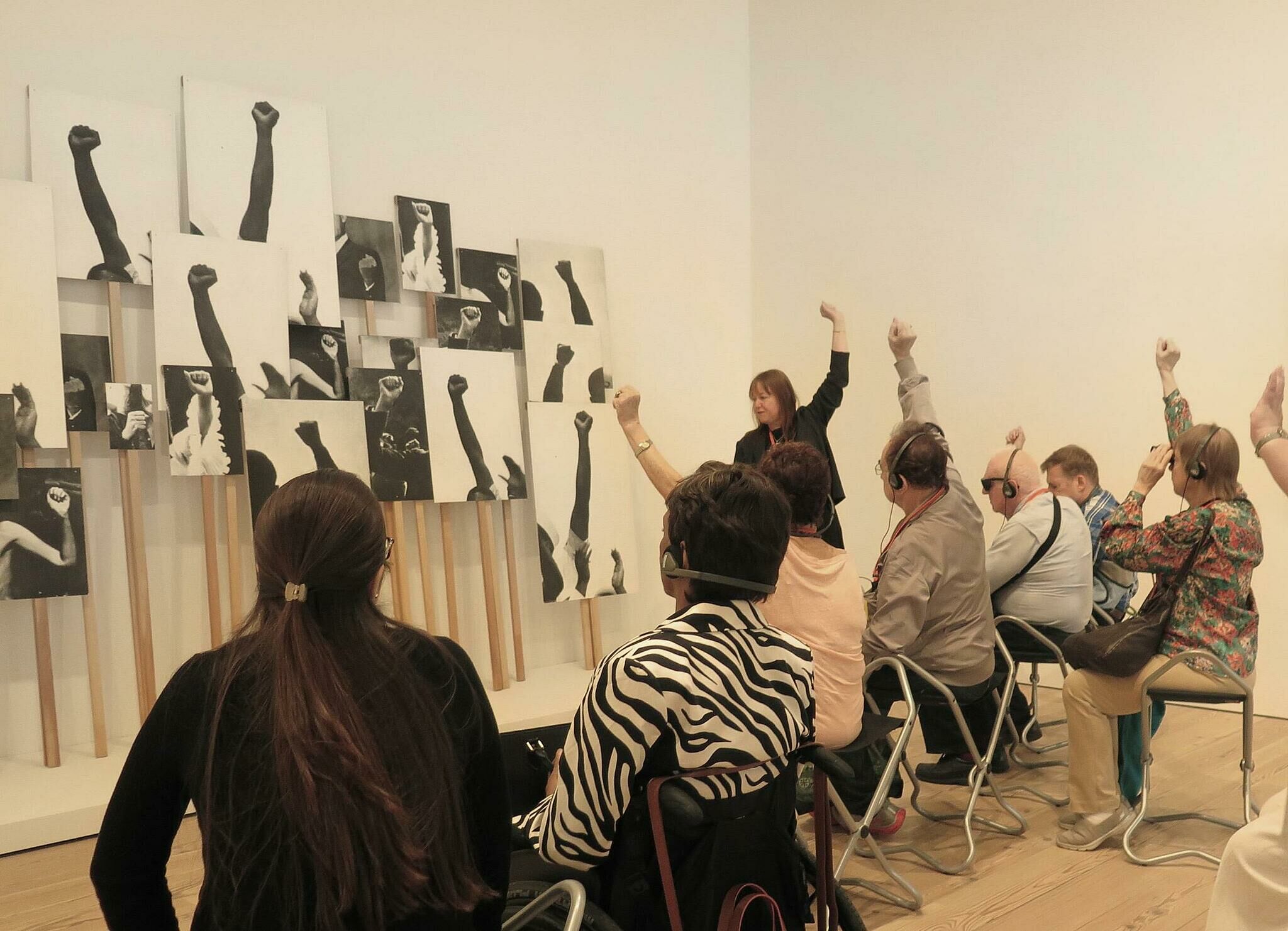 People sit down and raise their hands in the gallery