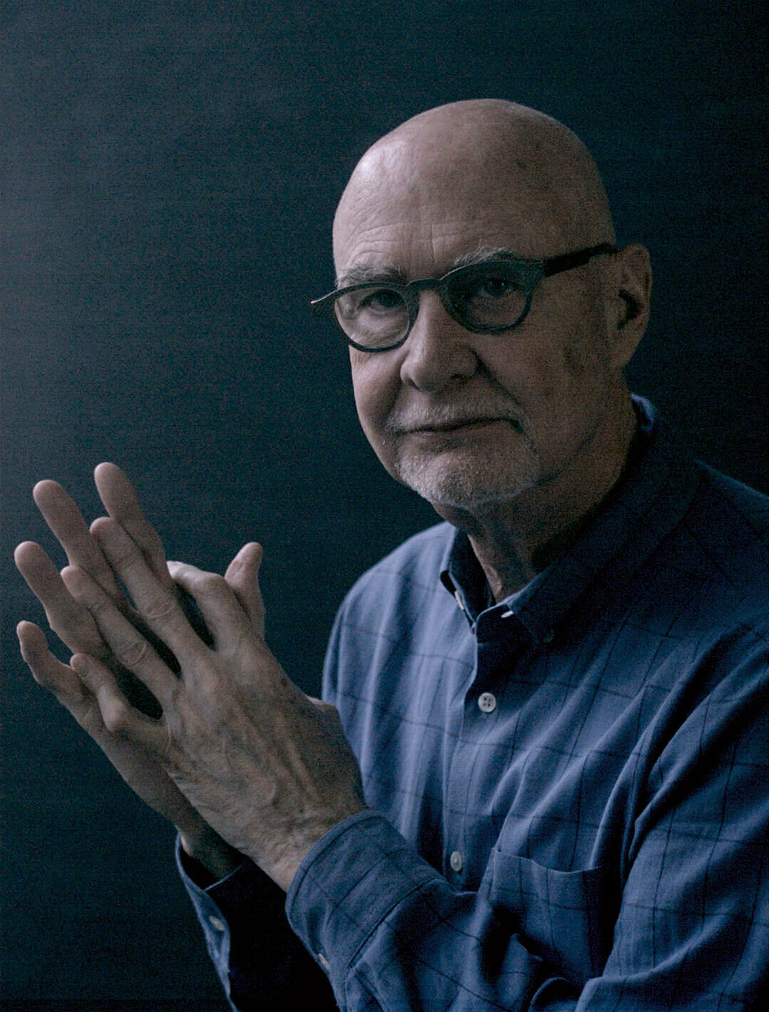 A still from a video work by James Nares. Art historian Douglas Crimp clasps his hands and looks directly at the camera
