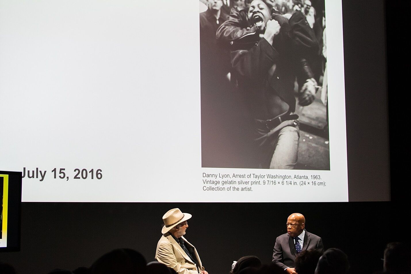 The two panelists on stage with a Civil Rights photograph displayed above.